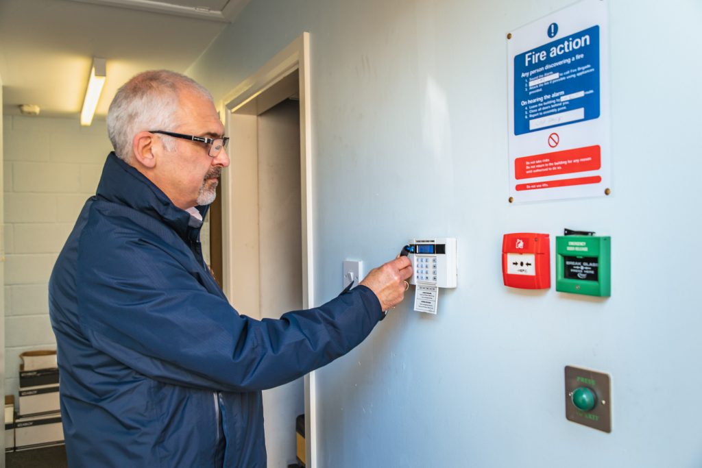 Man setting a burglar alarm. 